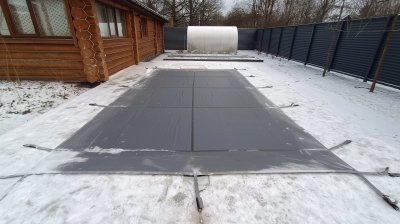 Уличный бассейн с темно-серым защитным тентом и снегом вокруг